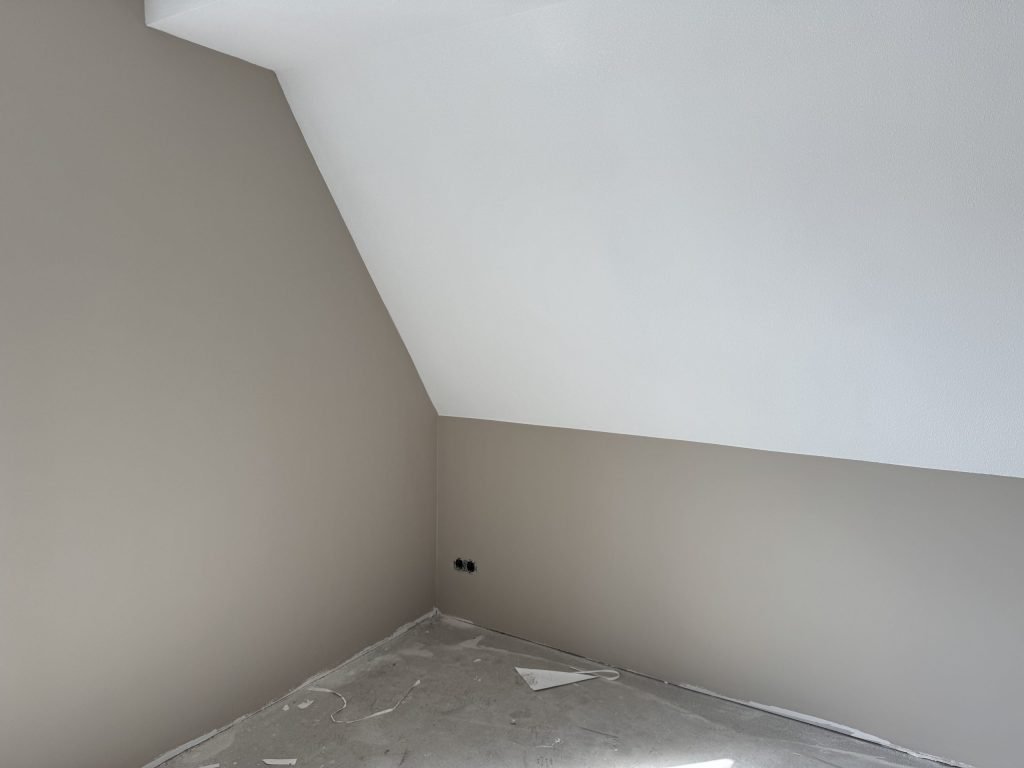 Zolderkamer in een nieuwbouwwoning met een schuine wand en een afgedekte vloer
